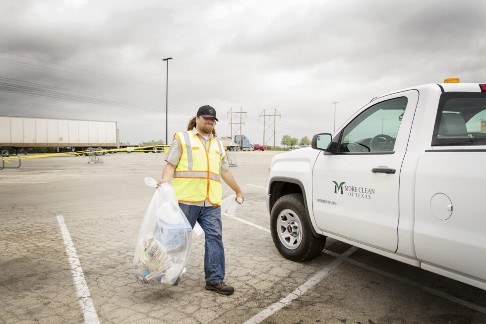 More Clean of Texas employee providing Day Porter Services carrying trash he's just emptied to his company truck