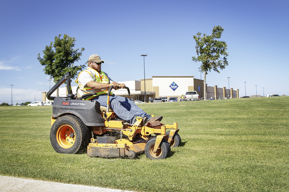 employee using a zero turn commercial mower to mow the grass of a commercial client