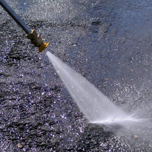 Pressure Washing nozzle spraying high pressure water onto asphalt