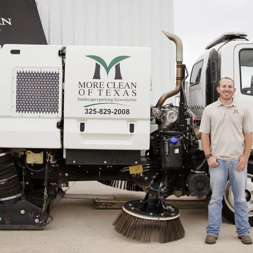 More Clean of Texas president Cole Watts standing in front of a sweeper truck