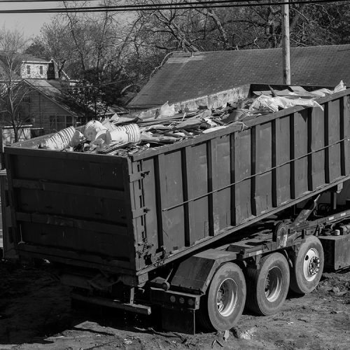 More Clean of Texas Debris Haul Off truck picking up roll off dumpster in black and white